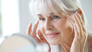 Older woman looking at fine lines in mirror