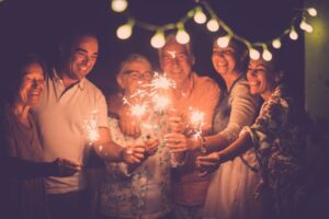 group of smiling friends with sparklers outside